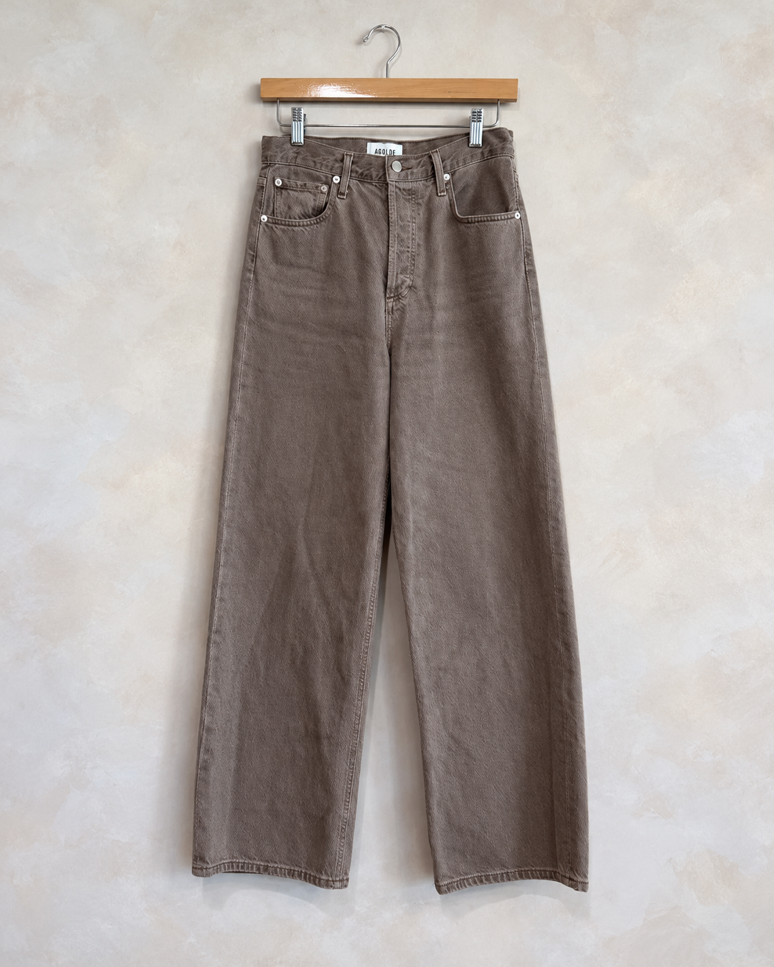 AGOLDE brown denim jeans on wooden clip hanger