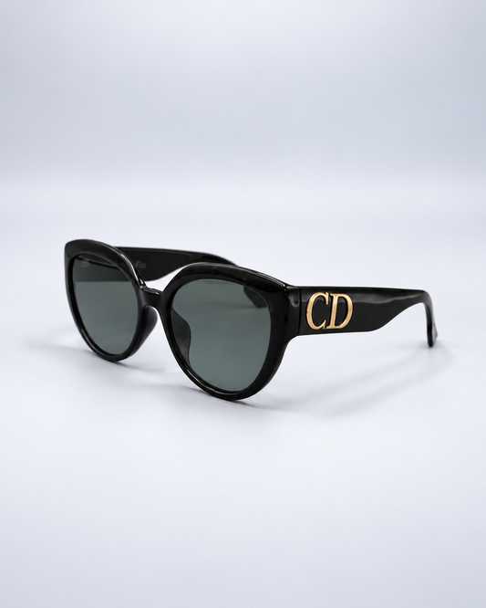 Christian Dior black sunglasses with gold CD detail on a pale gray studio background
