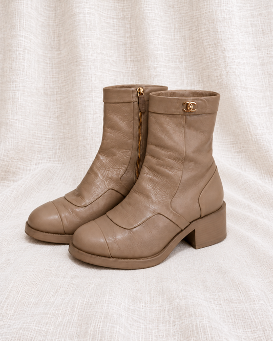 CHANEL Beige Leather CC Moto Boots — closely grouped left-facing pair on ivory linen
