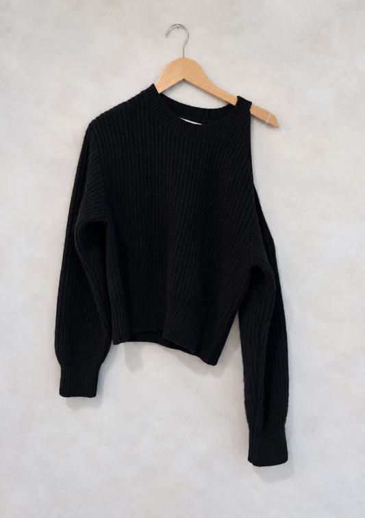 Sweater on wooden hanger against light gray plaster wall