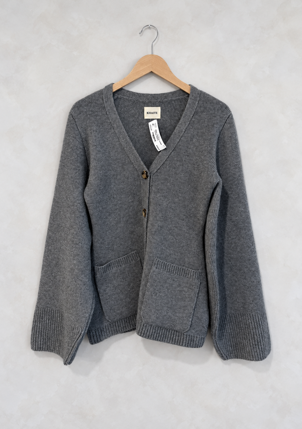 Sweater on wooden hanger against light gray plaster wall