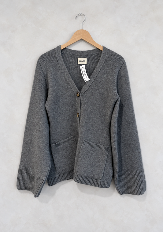 Sweater on wooden hanger against light gray plaster wall