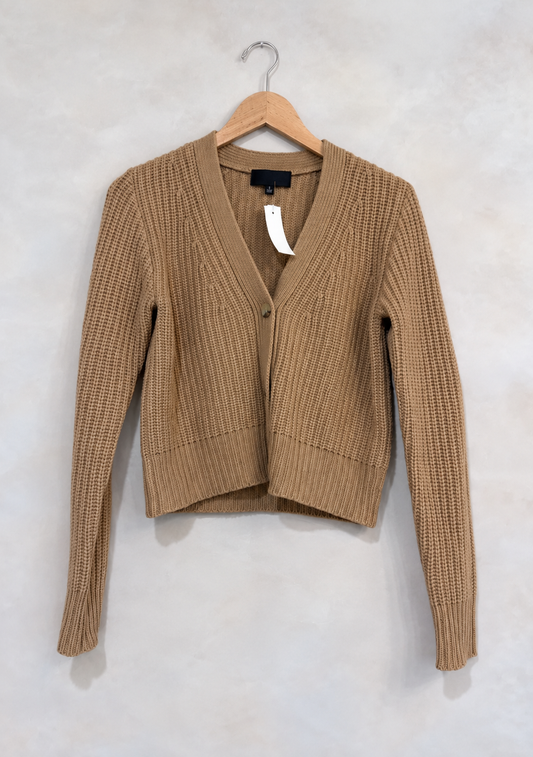 Sweater on wooden hanger against light gray plaster wall