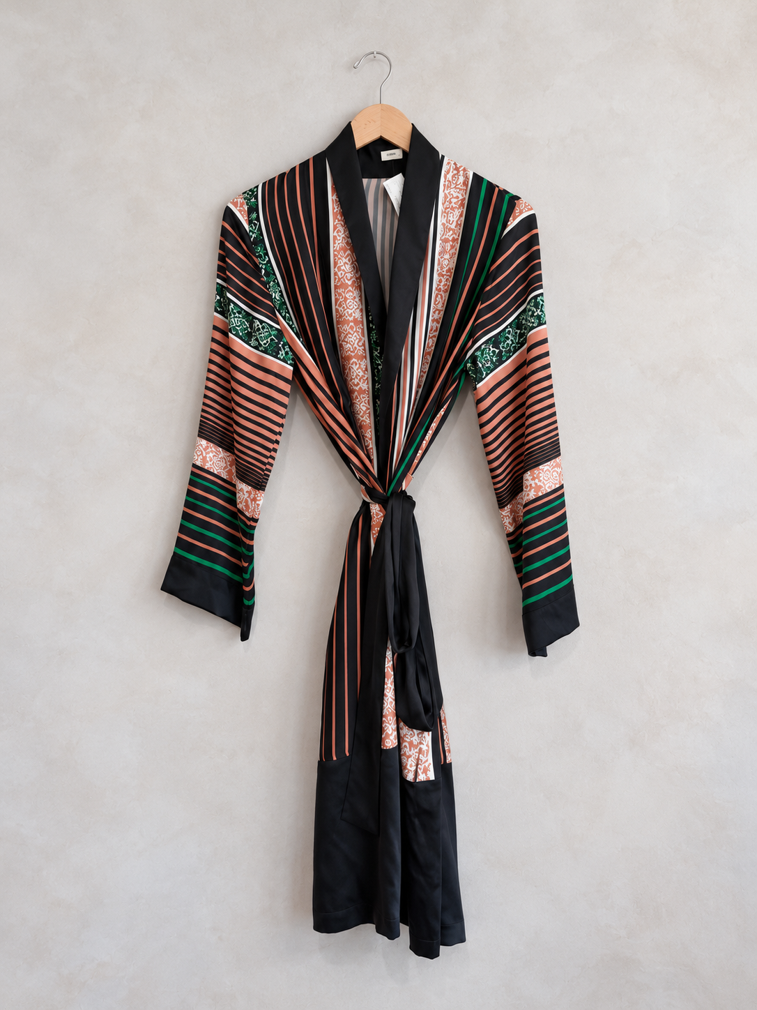 Garment on a wooden hanger against a pale textured wall