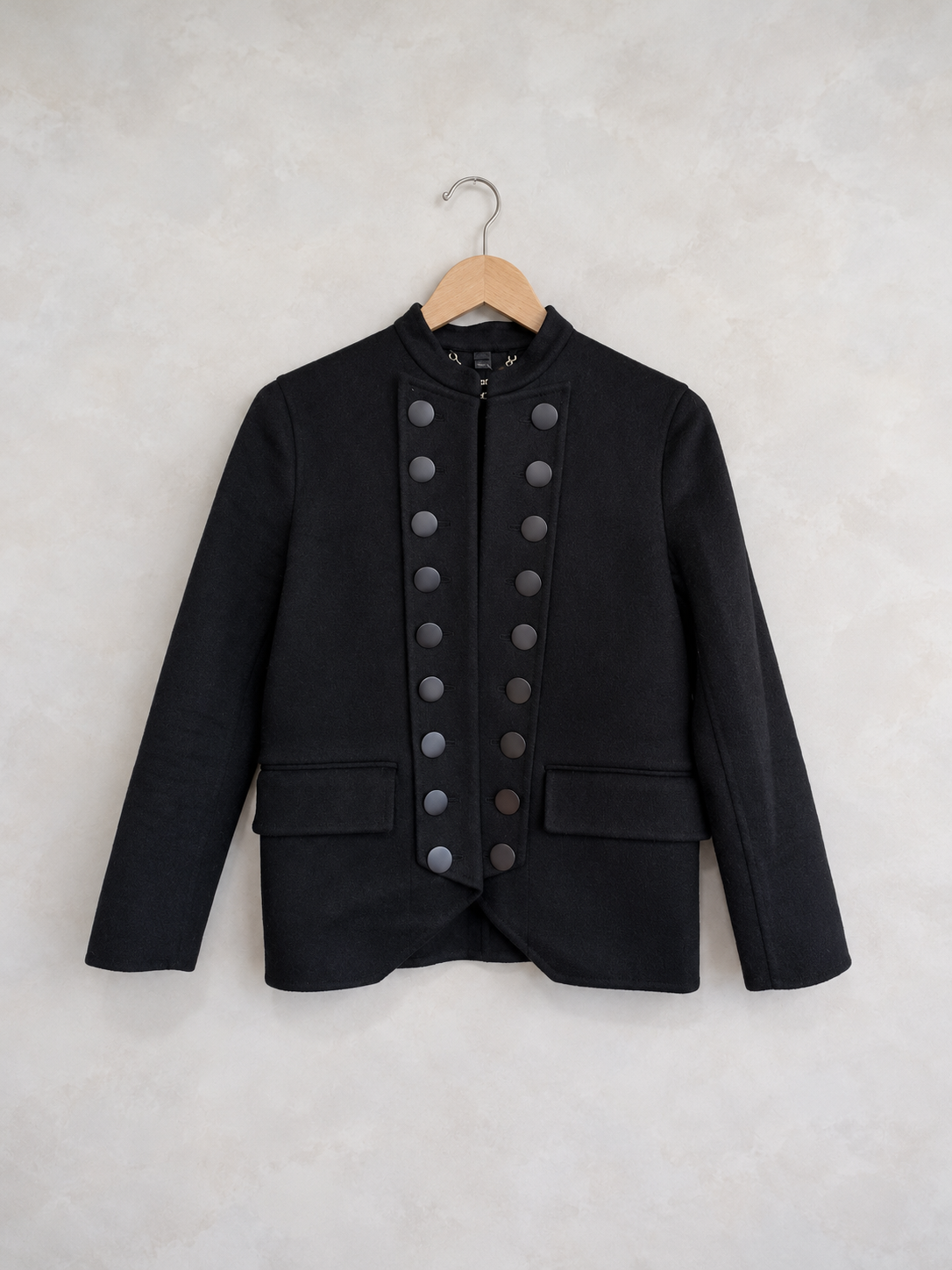 Garment on a wooden hanger against a pale textured wall