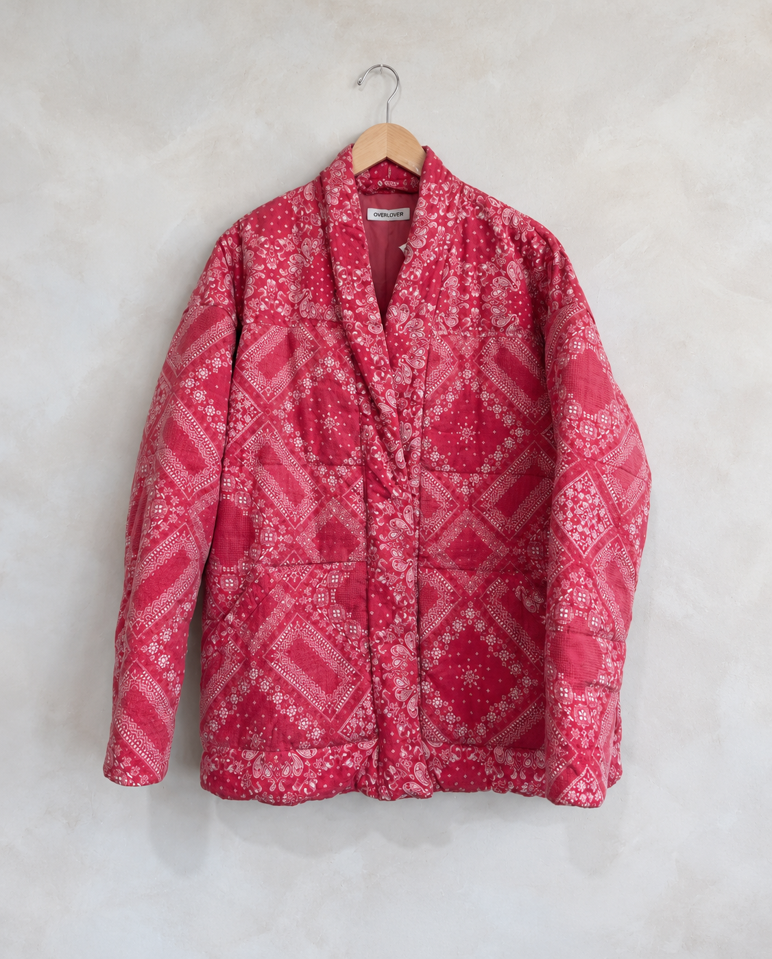 Garment on wooden hanger against pale textured wall
