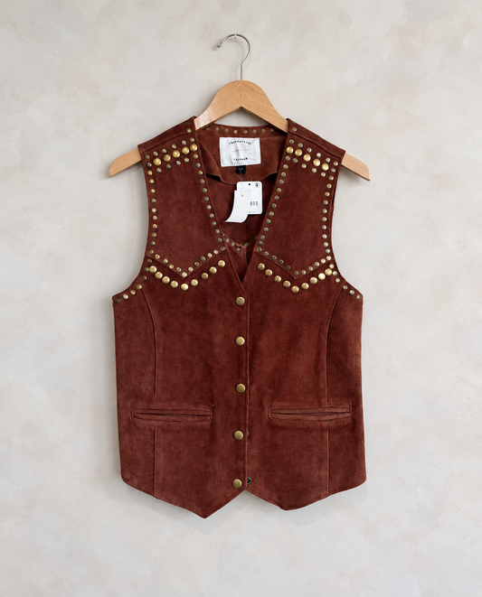 Garment on wooden hanger against pale textured wall