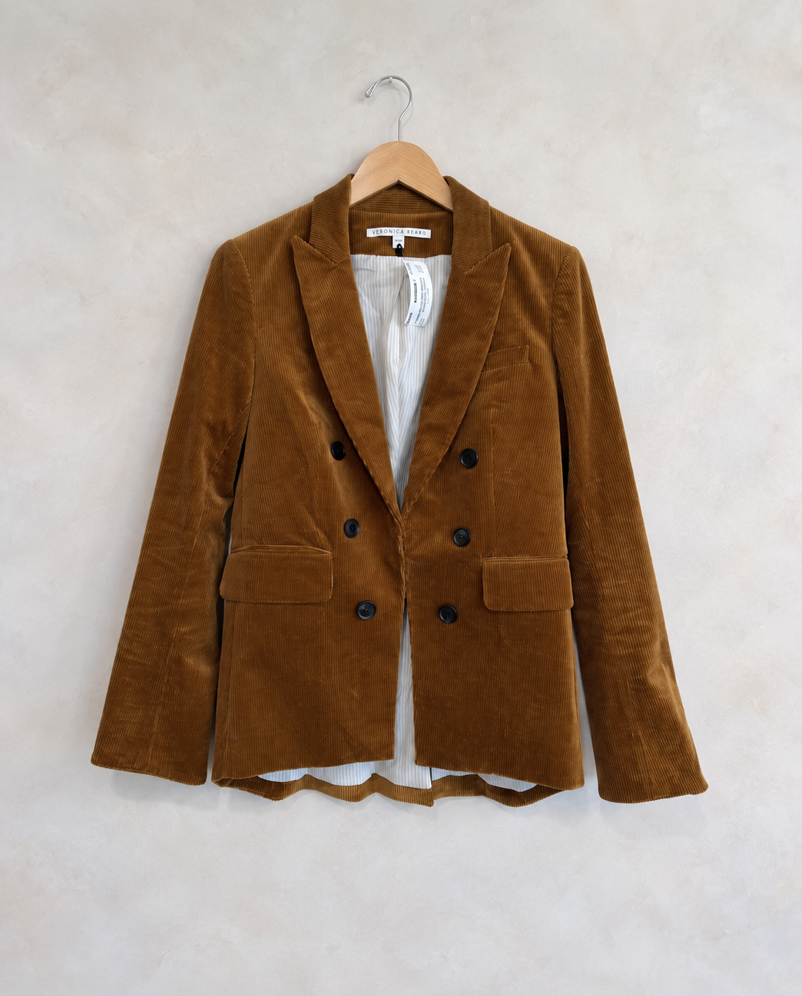 Garment on wooden hanger against pale textured wall