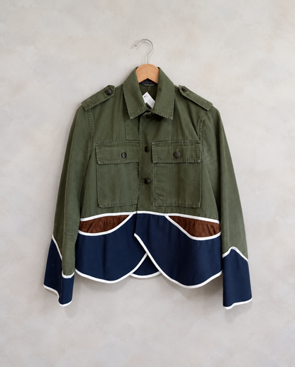 Harvey Faircloth pieced cropped jacket photographed on a wooden hanger against a pale neutral textured wall