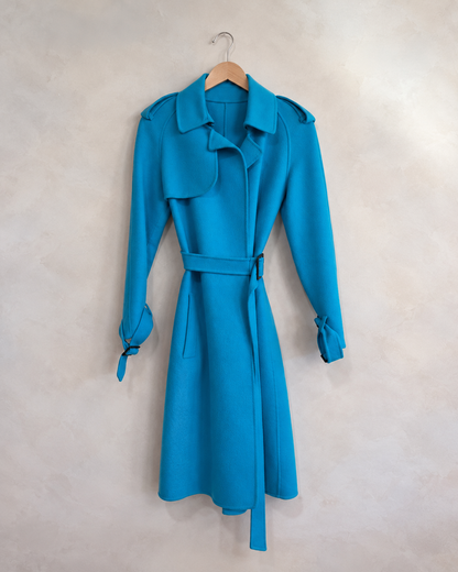 Bottega Veneta turquoise cashmere wrap trench photographed on a wooden hanger against a pale neutral textured wall