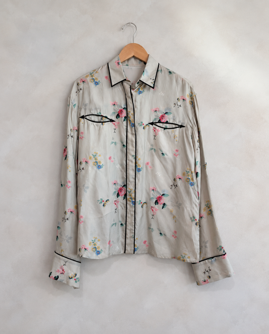 Haider Ackermann floral western shirt photographed on a wooden hanger against a pale neutral textured wall