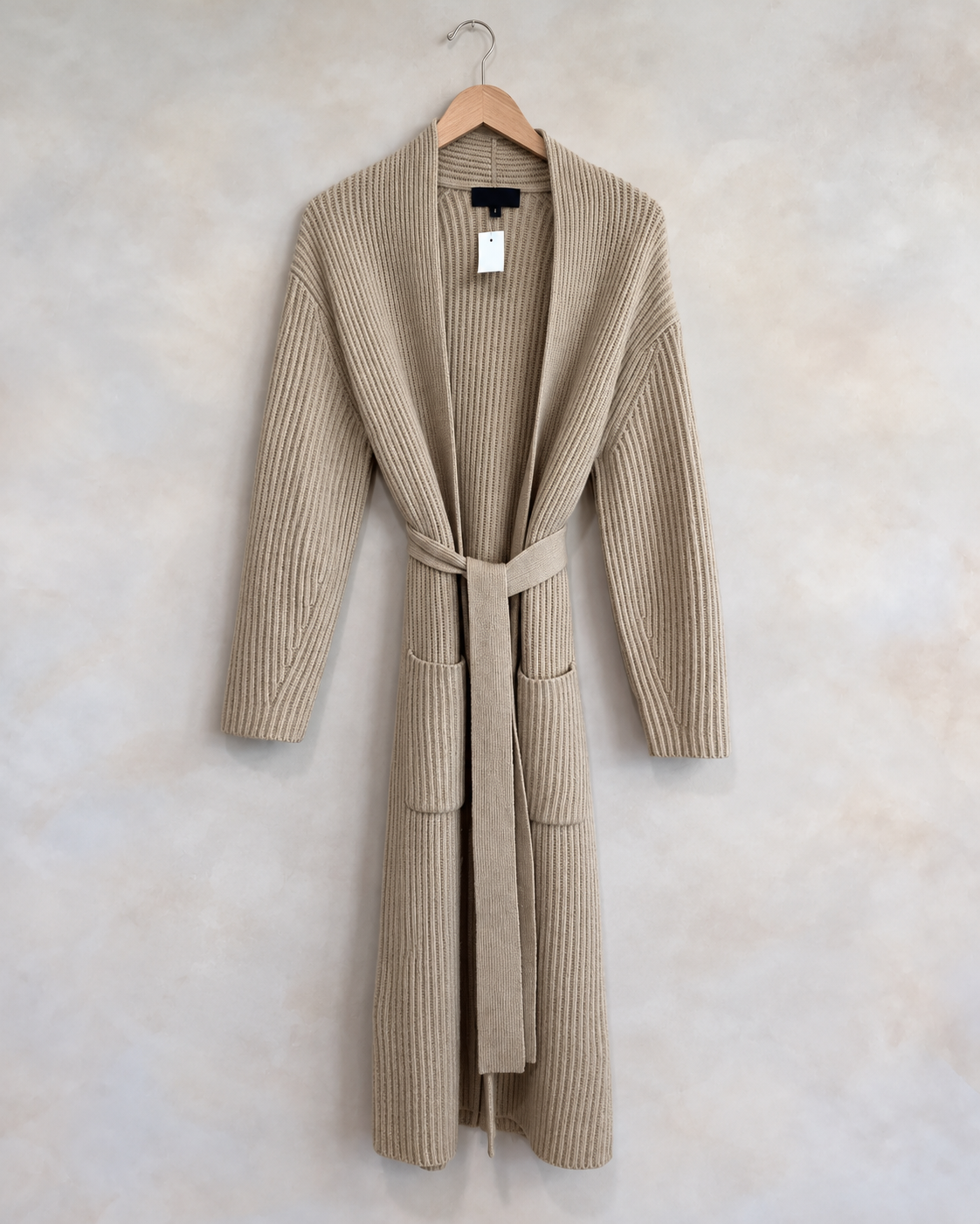 Nili Lotan garment on wooden hanger against pale textured wall