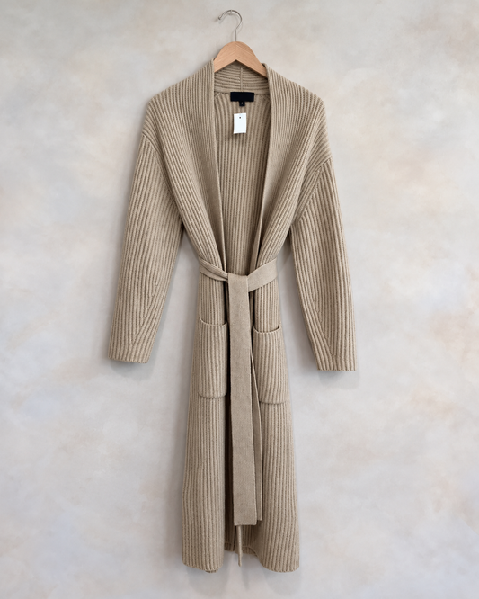 Nili Lotan garment on wooden hanger against pale textured wall
