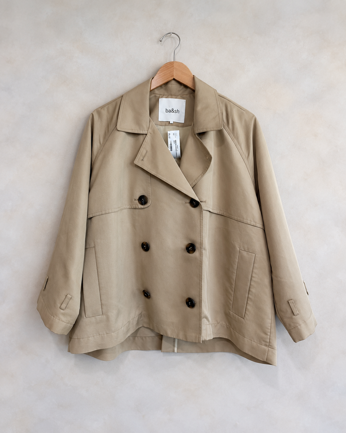 BA&SH garment on wooden hanger against pale textured wall
