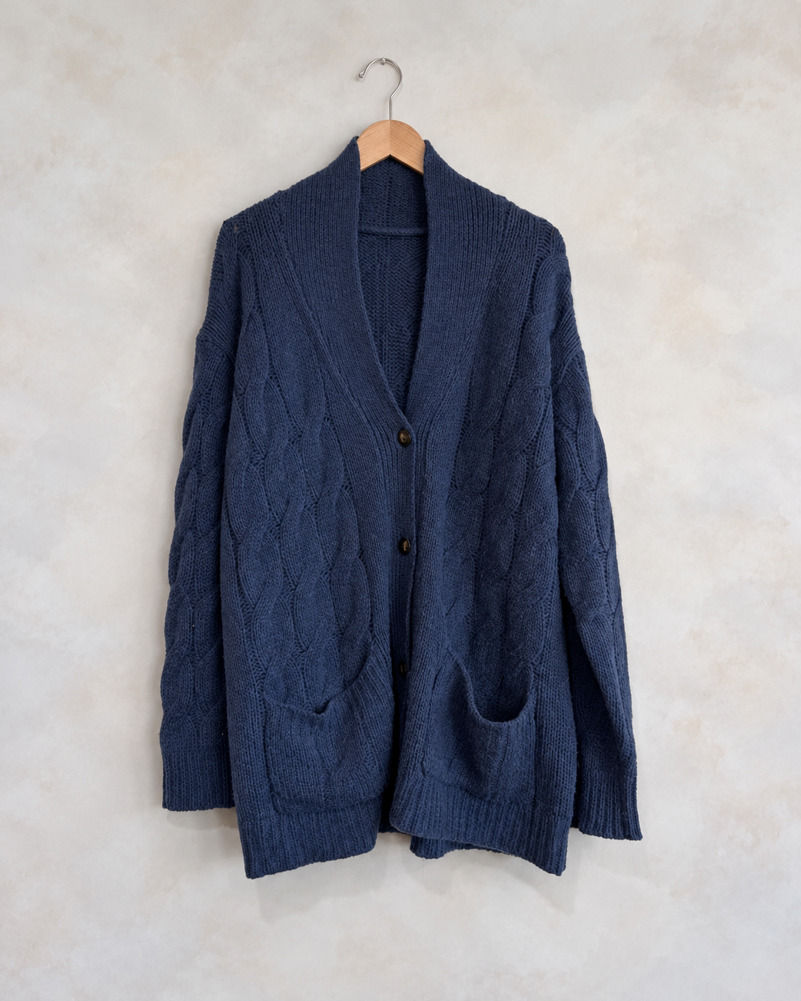 SABLYN, 100% Cashmere Cable Knit Cardigan, 4-10 on a wooden hanger against a softly mottled pale wall