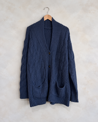 SABLYN, 100% Cashmere Cable Knit Cardigan, 4-10 on a wooden hanger against a softly mottled pale wall