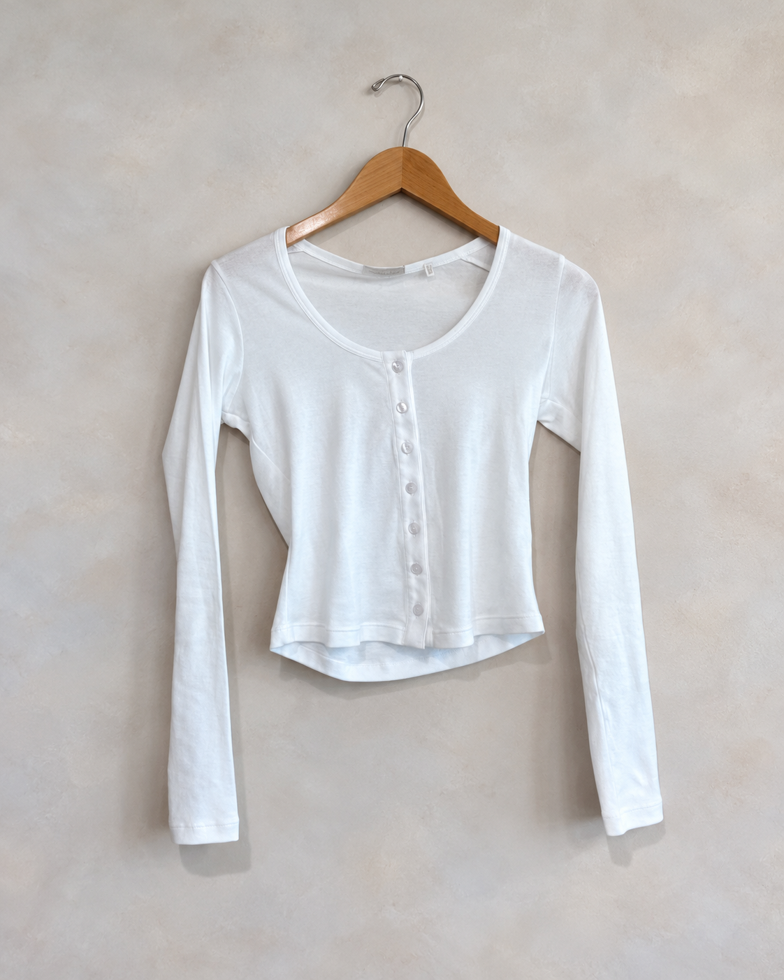 LEONARD FRISBIE, 100% Cotton Casey Cardigan, XS on a wooden hanger against a softly mottled pale wall