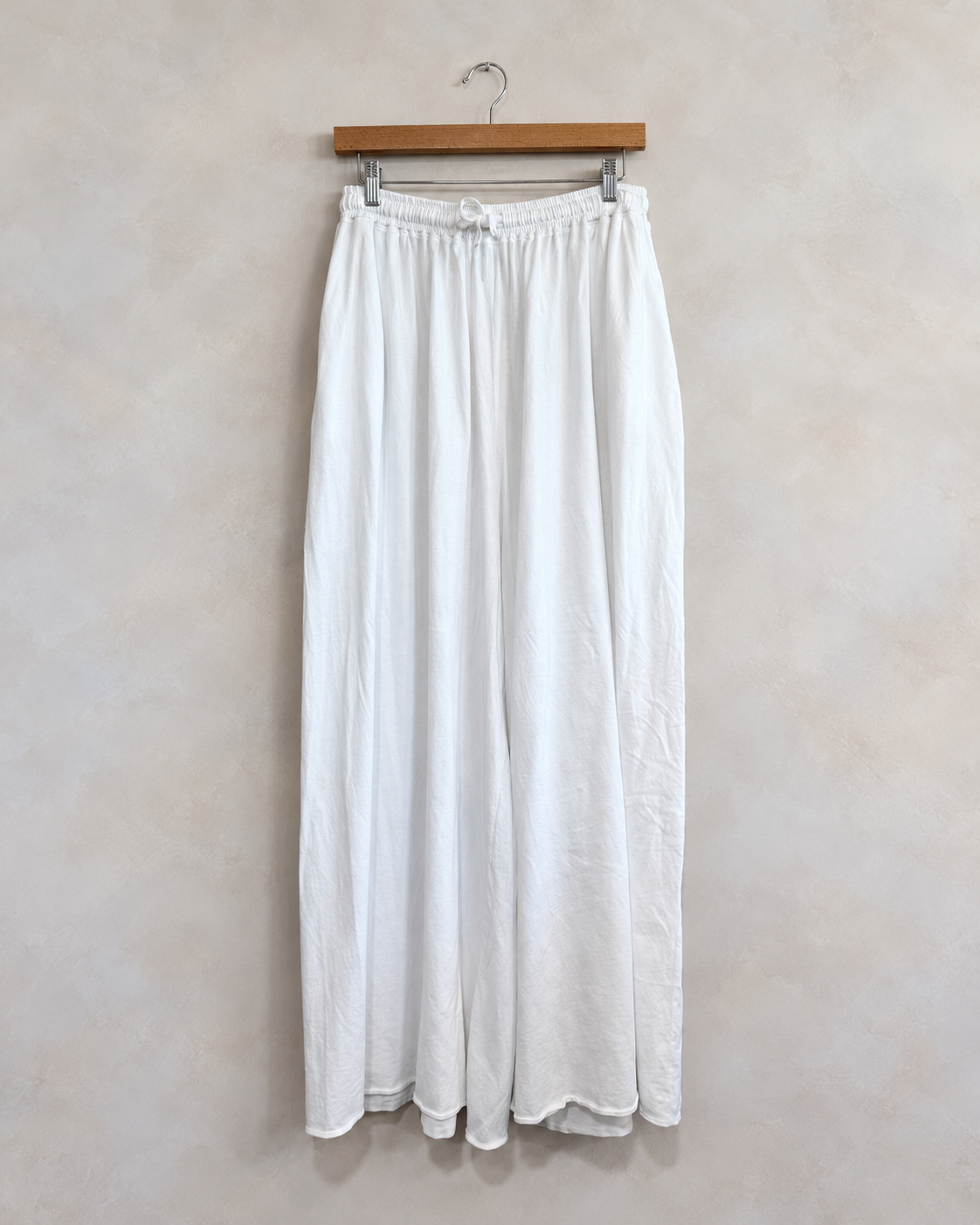 LEONARD FRISBIE, Maxi Jersey Pants, XS/S on a wooden hanger against a softly mottled pale wall
