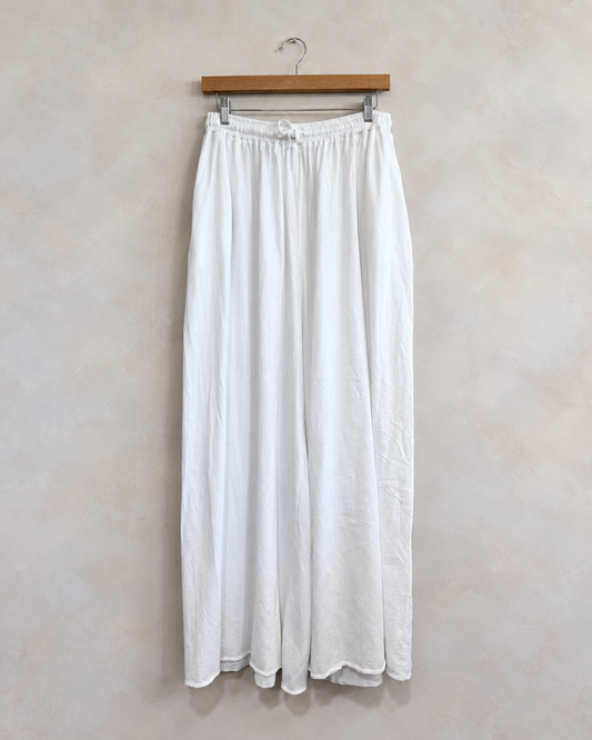 LEONARD FRISBIE, Maxi Jersey Pants, XS/S on a wooden hanger against a softly mottled pale wall