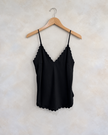 A.L.C black scalloped tank on a wooden hanger against a softly mottled pale wall